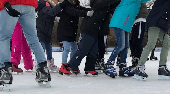 Multitud de pies de personas patinando sobre hielo.